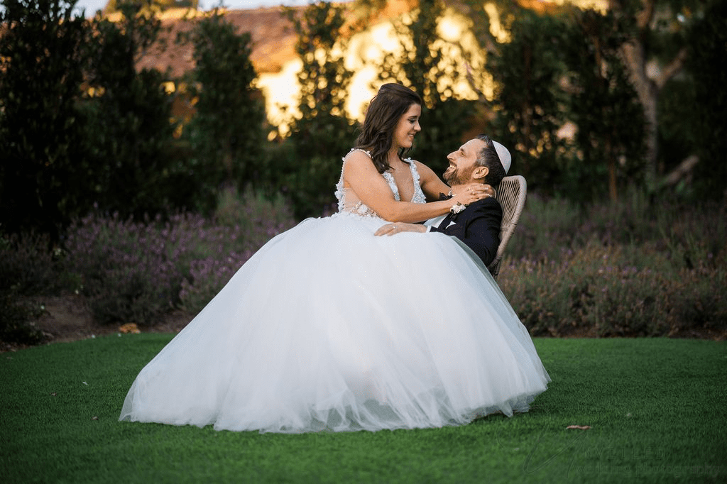 La Jolla Wedding Photographer: Bride sitting on groom's lap in a lush garden setting.