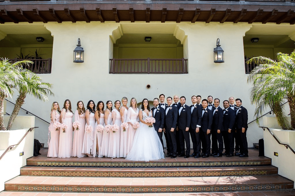Large wedding party in blush dresses and tuxedos. La Jolla Wedding Photographer captures the couple.