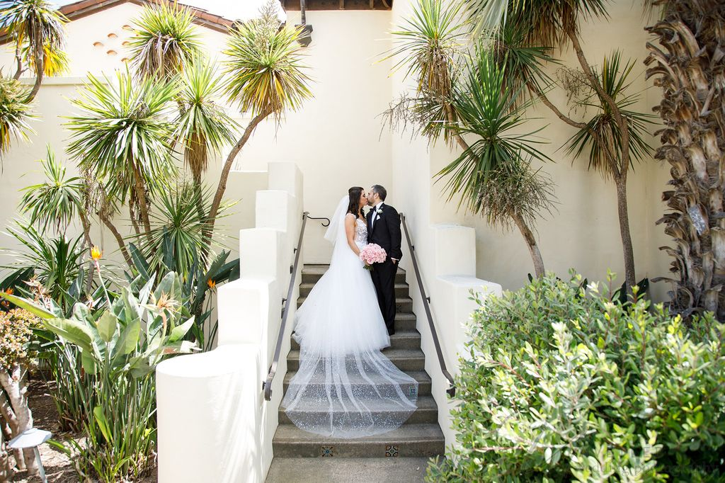 La Jolla Wedding Photographer portrait of a couple kissing on stairs surrounded by palm trees.