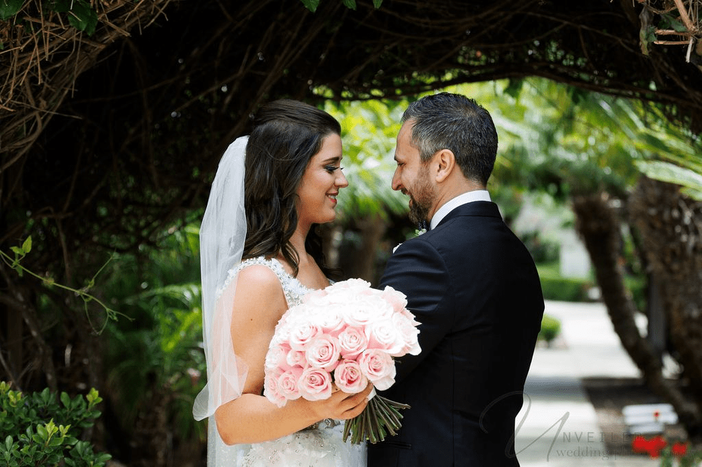 A smiling bride and groom embrace in a garden, captured by a La Jolla Wedding Photographer.