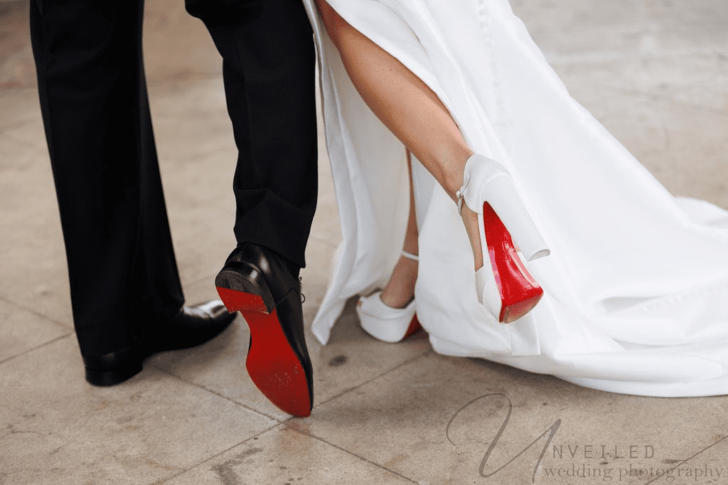 Close-up of bride and groom showing off red-soled wedding shoes at a San Diego elopement.
