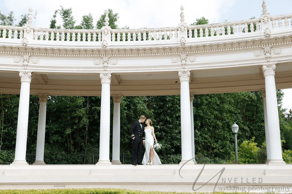 Groom dips and kisses his bride during their San Diego elopement at a scenic white colonnade.