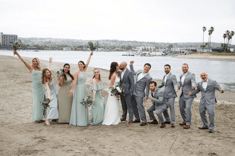 True-to-life color wedding party celebrating on beach with bride, groom, and bridesmaids in sage green
