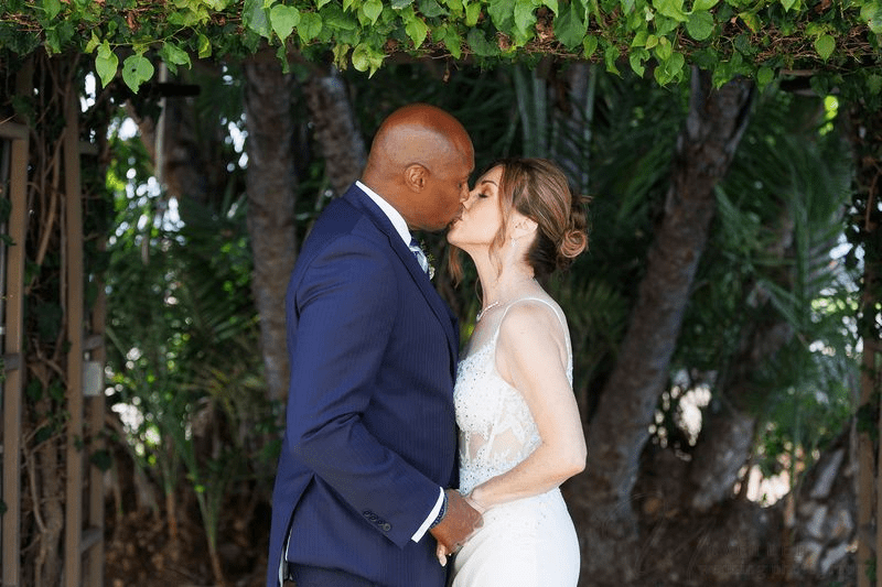 Couple kissing at a San Diego Courthouse Wedding Photography session under lush greenery.