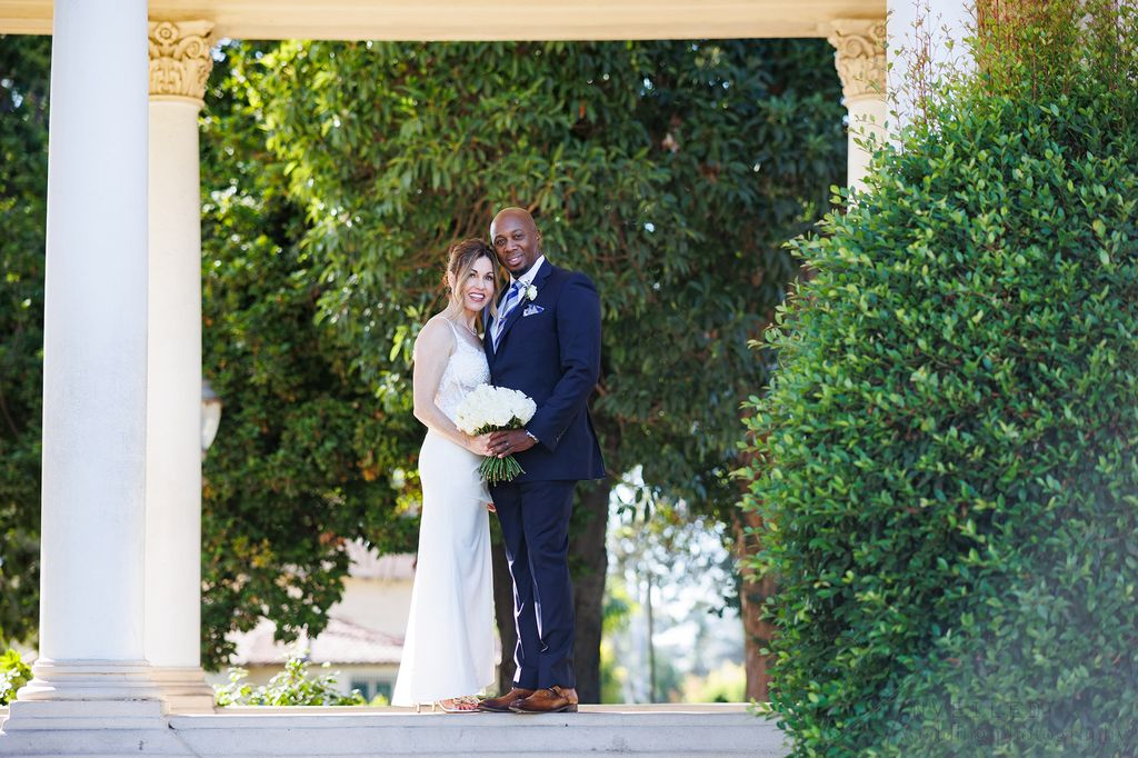 Newlyweds posing outdoors for San Diego Courthouse Wedding Photography by a garden pillar.