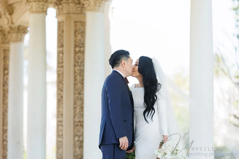 Best remodeler in Dallas, TX: A bride and groom kissing outdoors by ornate pillars.