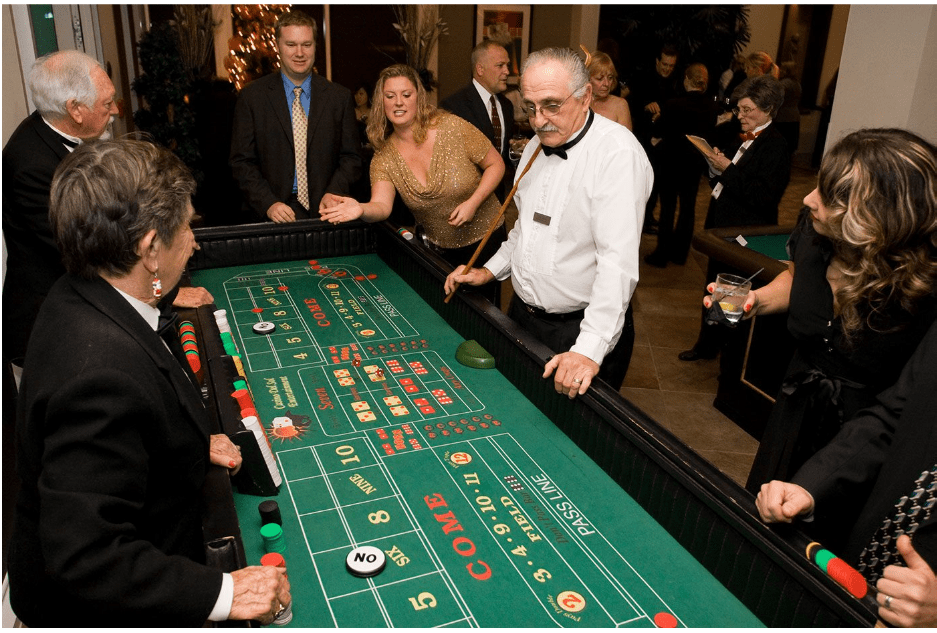 People in formal wear mingling at an upscale outdoor rooftop lounge party at night.