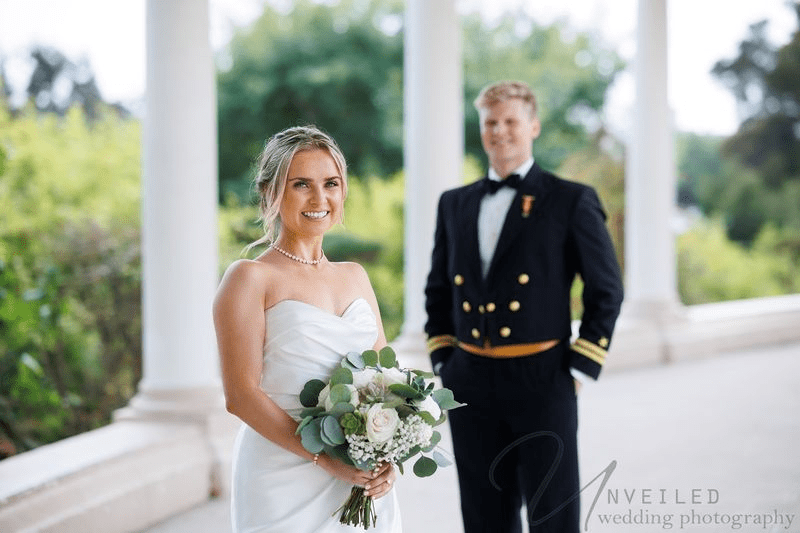 Newlywed couple gazing at each other under a bridal veil in an outdoor setting