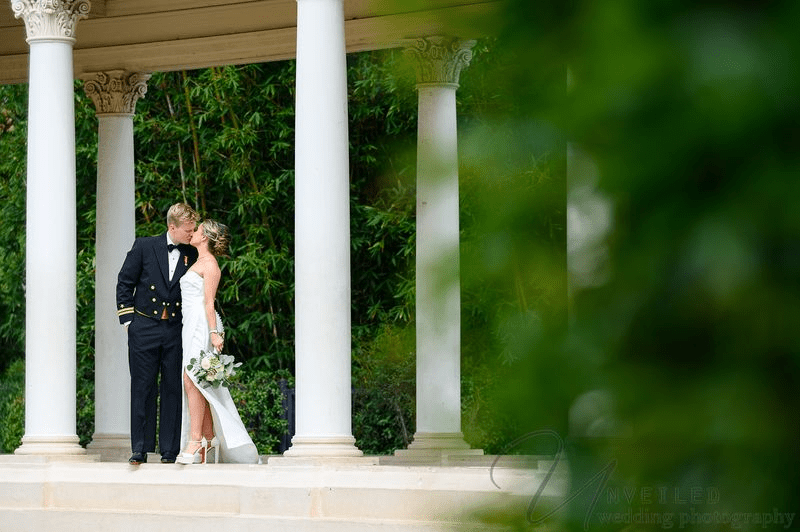 Bride and groom sharing a romantic moment under wedding veil outdoors
