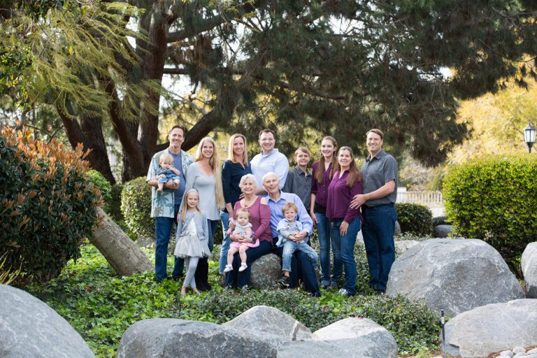 A large multi-generational family posing together for a photo in a park.
