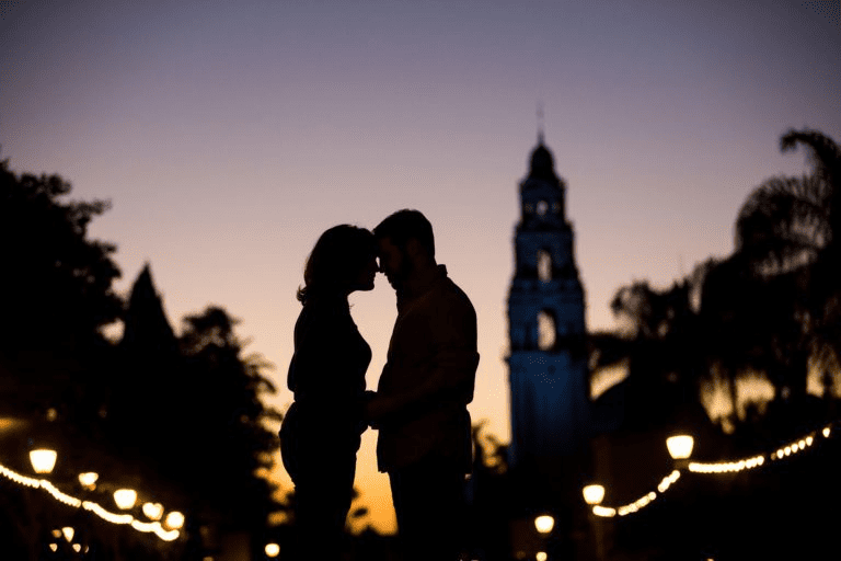Silhouette of a romantic couple holding hands at sunset with a tower background.