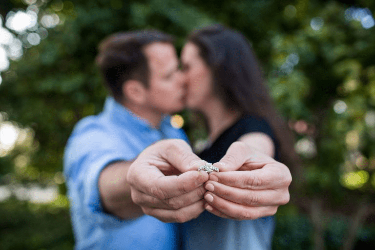 Mungni ki angoothi ka close-up shot jabki piche couple ek doosre ko kiss kar raha hai.