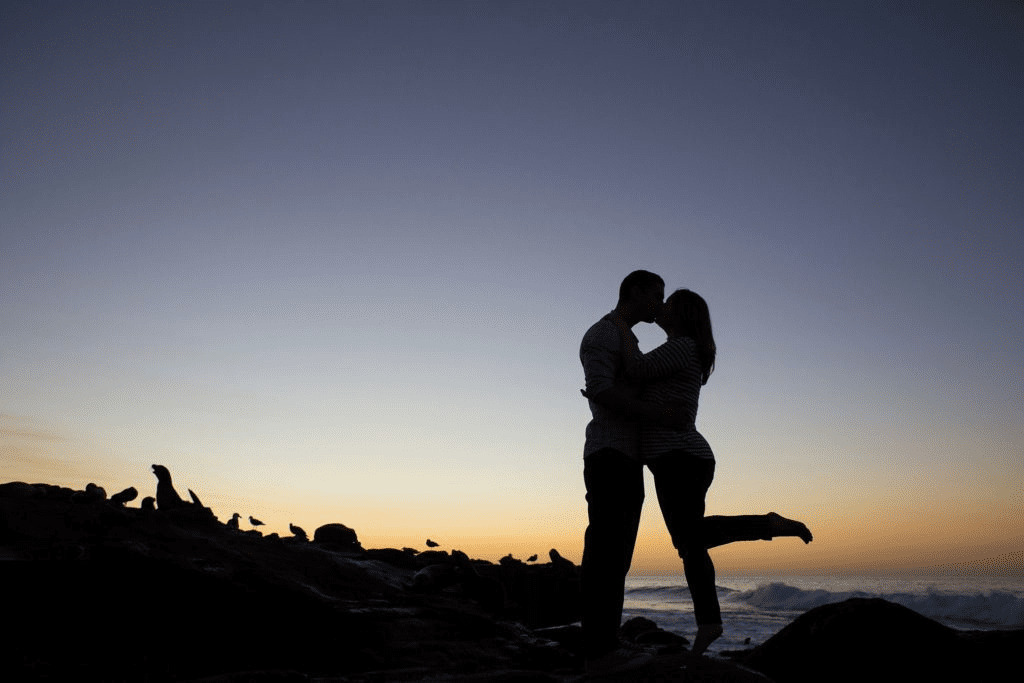 A striking silhouette of a couple sharing an intimate kiss against a vast, minimalist gradient background of a fading evening sky.