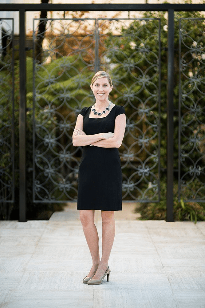 San Diego corporate headshots of a smiling professional woman in business attire, captured outdoors with natural light and clean blurred background.