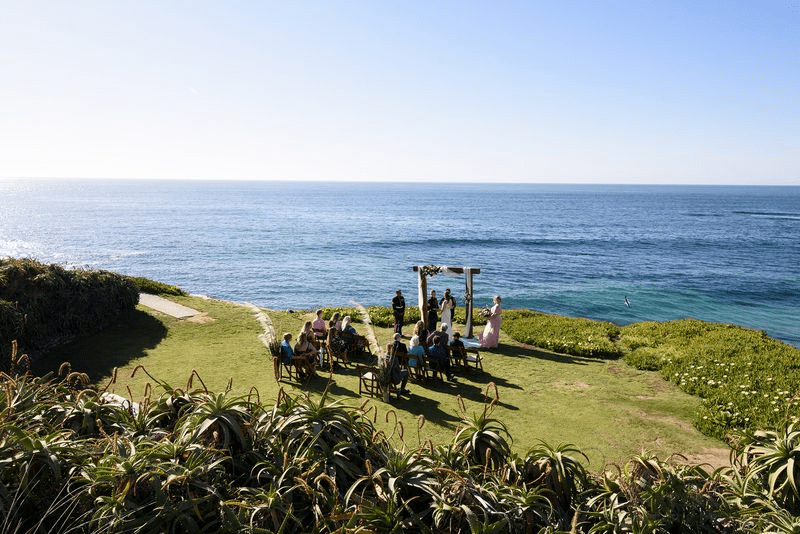 A scenic seaside wedding setup with a wooden altar on a bright sunny day.