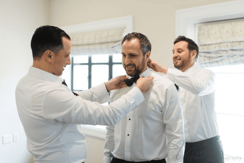 A groom getting ready with his groomsmen by Unveiled Wedding Photography.