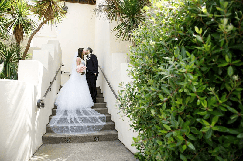 Estancia La Jolla wedding photography featuring a bride and groom kissing outdoors.