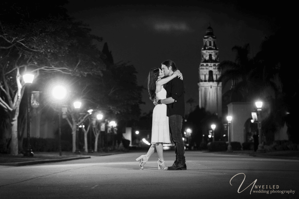 Couple kissing at night by California Tower—engagement photographer cost San Diego.