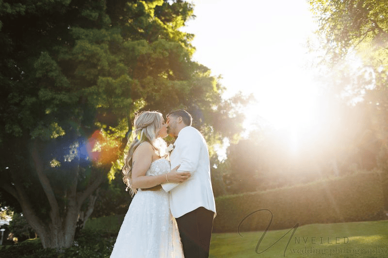 Bride and groom kissing at sunset outside Grand Tradition Fallbrook.