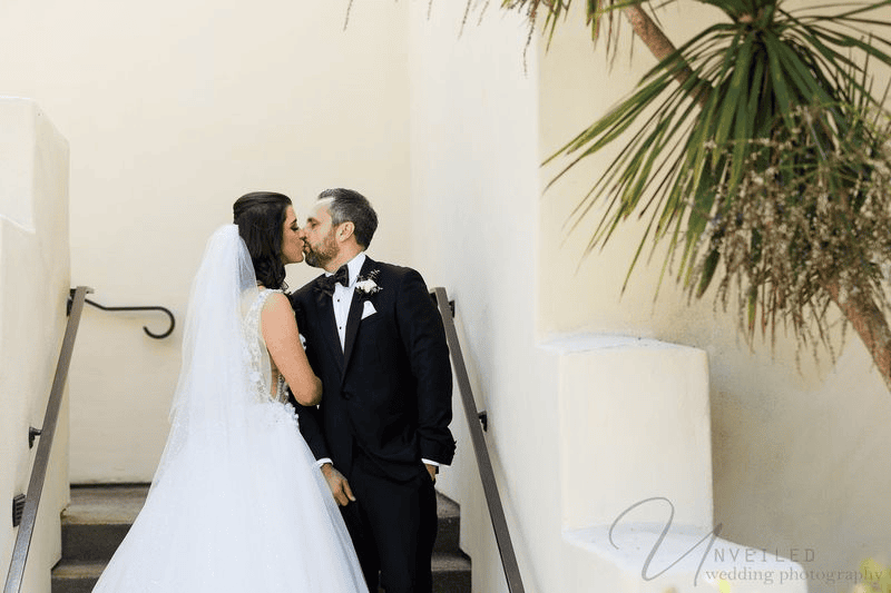 Bride and groom kissing on stairs at small wedding venues in San Diego.