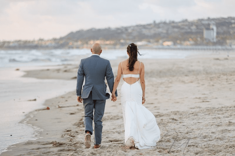 A scenic seaside wedding stroll portrait by Unveiled Wedding Photography.