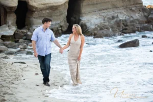 Couple walking along rocky cove beach: outdoor San Diego engagement photo locations.