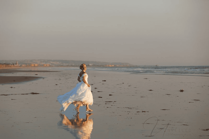 Bride walking barefoot along the ocean shore: intimate wedding in San Diego.
