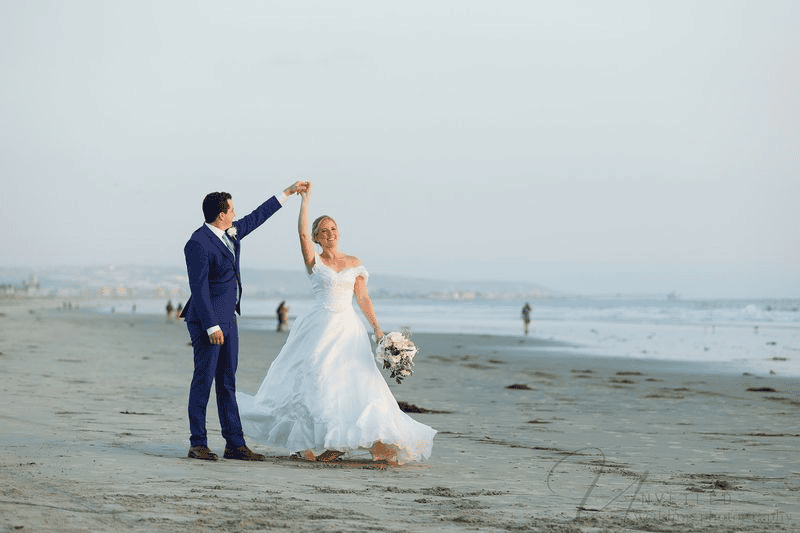 Bride and groom dancing on beach shoreline: intimate wedding in San Diego.