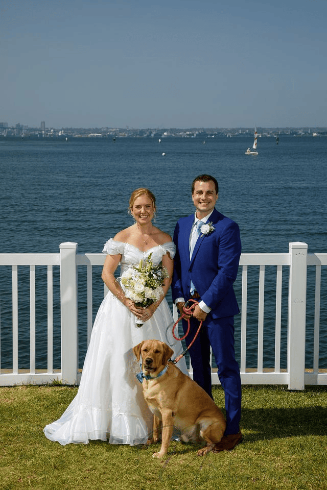 Bride and groom posing with their dog by ocean during intimate wedding in San Diego.