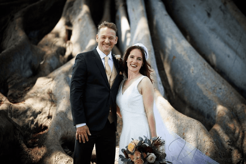 Bride and groom posing by tree roots during multi-day San Diego wedding weekend.