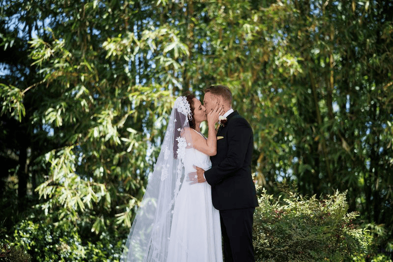 Bride and groom kissing in front of bamboo trees: multi-day San Diego wedding weekend.