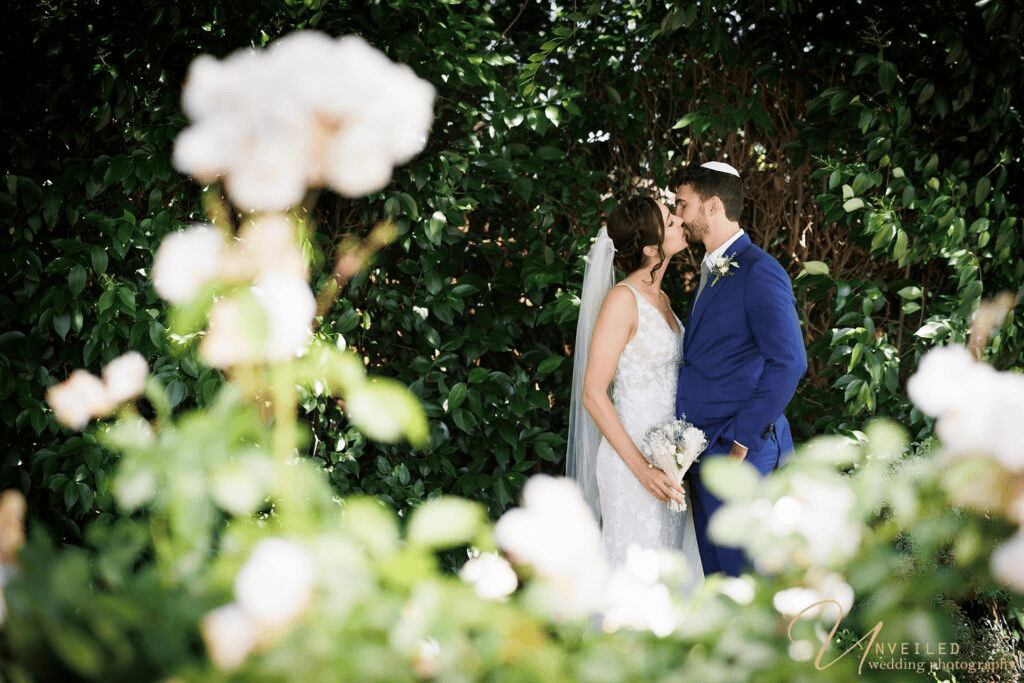 Bride and groom kissing behind flowers for Wedding Album vs Digital Gallery selection.