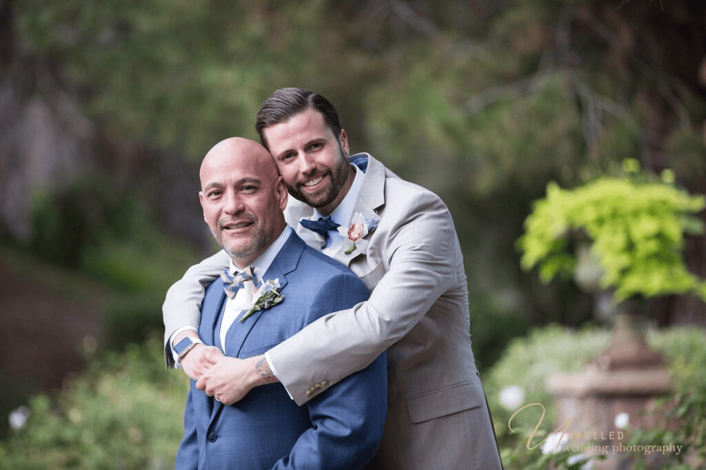 Groom hugging partner from behind shot by same-sex wedding photographer in San Diego.