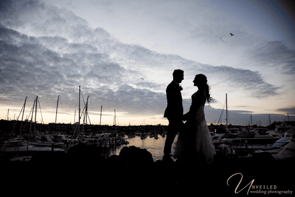 Silhouette portrait of couple at sunset marina: Wedding Photography Coverage.