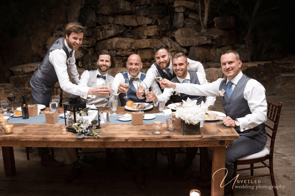 Groom party raising a toast at dinner by same-sex wedding photographer in San Diego.
