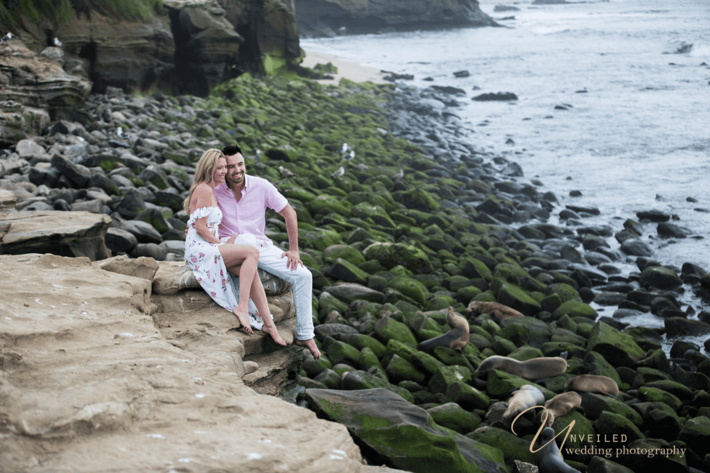 Couple sitting on cliff near seal cove for an engagement session before your wedding.
