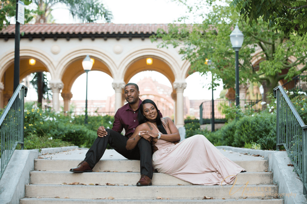 Couple sitting on stairs in park plaza for an engagement session before your wedding.