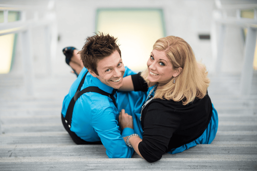 Playful couple sitting on outdoor stairs for an engagement session before your wedding.