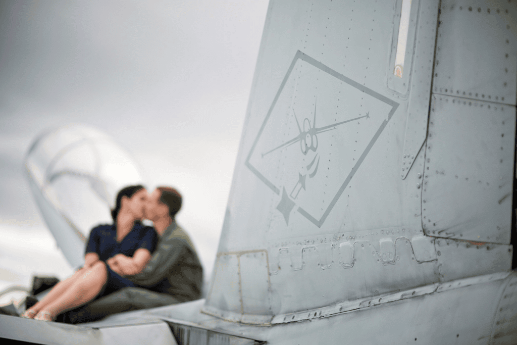 Military couple kissing on aircraft tail for an engagement session before your wedding.