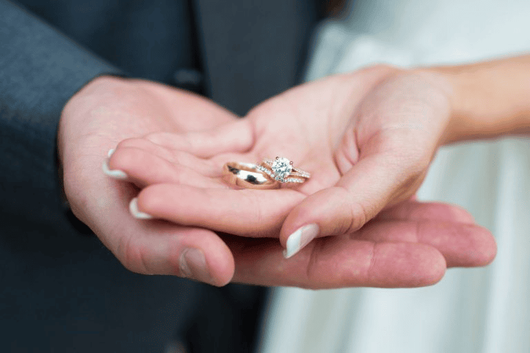 Couple holding wedding rings in palms showing Wedding Photography Trends 2027.