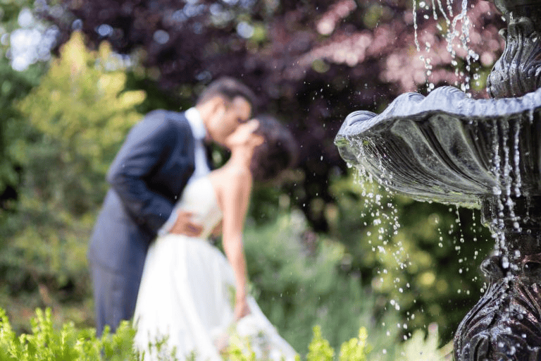 Bride and groom kissing behind water fountain for Wedding Photography Trends 2027.