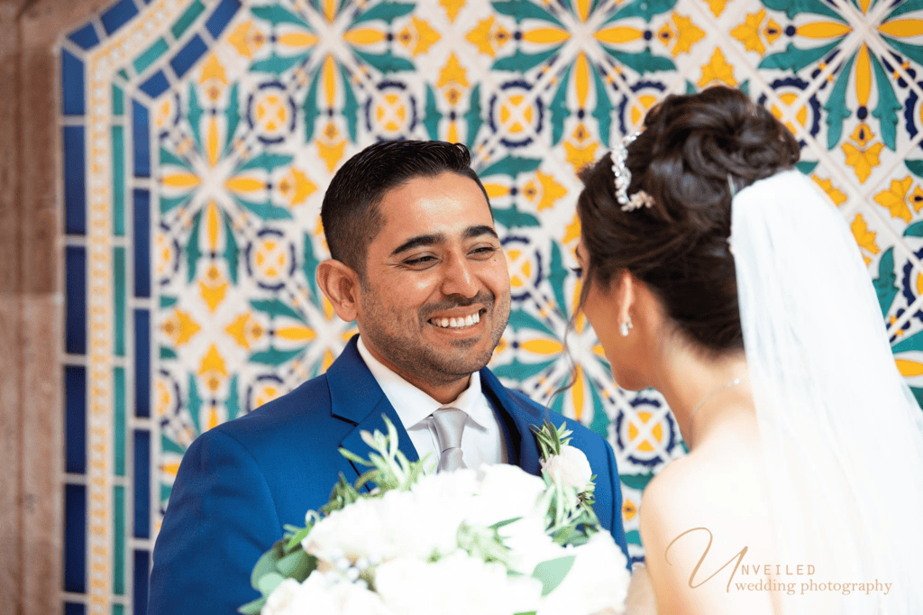 Groom smiling at bride against colorful tiled backdrop in Wedding photography shots.