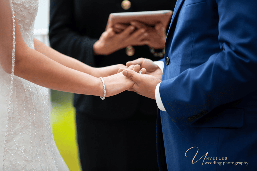 Close-up of bride and groom holding hands during vows in Wedding photography shots.