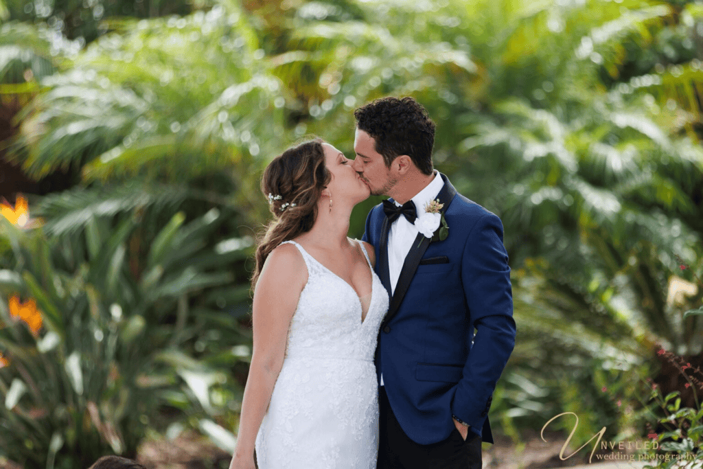 Bride and groom kissing in garden setting for Wedding Photography Coverage.