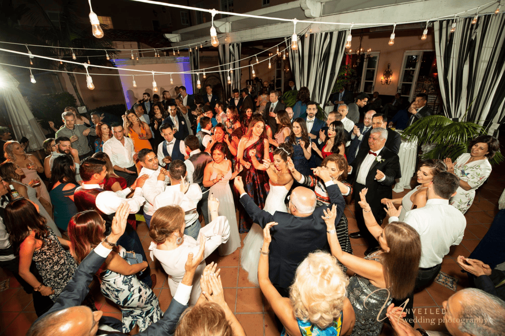Guests dancing at reception under string lights in party Wedding photography shots.