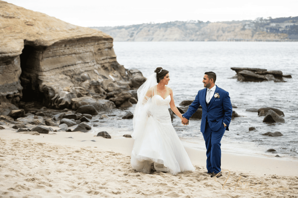 Bride and groom walking on beach by cliffside in romantic Wedding photography shots.