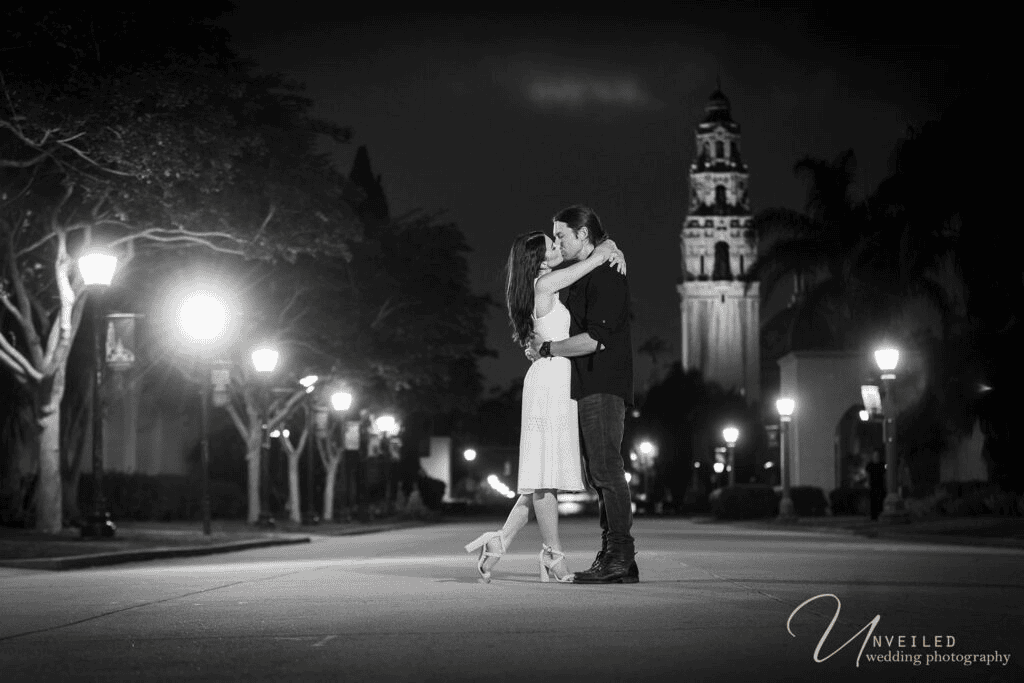 Black and white night portrait of couple kissing on street for Engagement Photo Ideas.