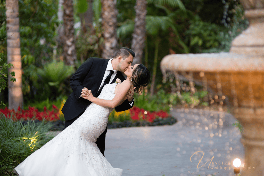 Groom dipping bride near fountain captured by Grand Tradition Estate Wedding Photographer.