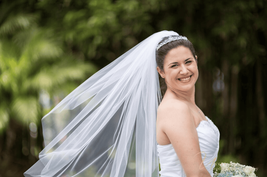 Smiling bride portrait with flowing veil in fine art vs documentary wedding photography.