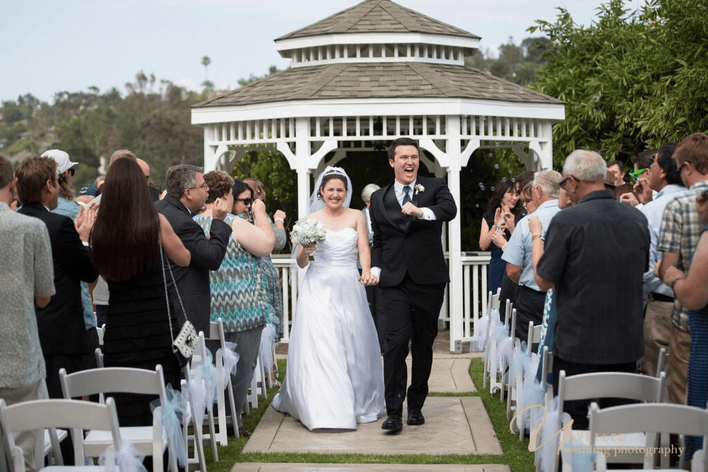 Cheering bride and groom walking down aisle in fine art vs documentary wedding photography.